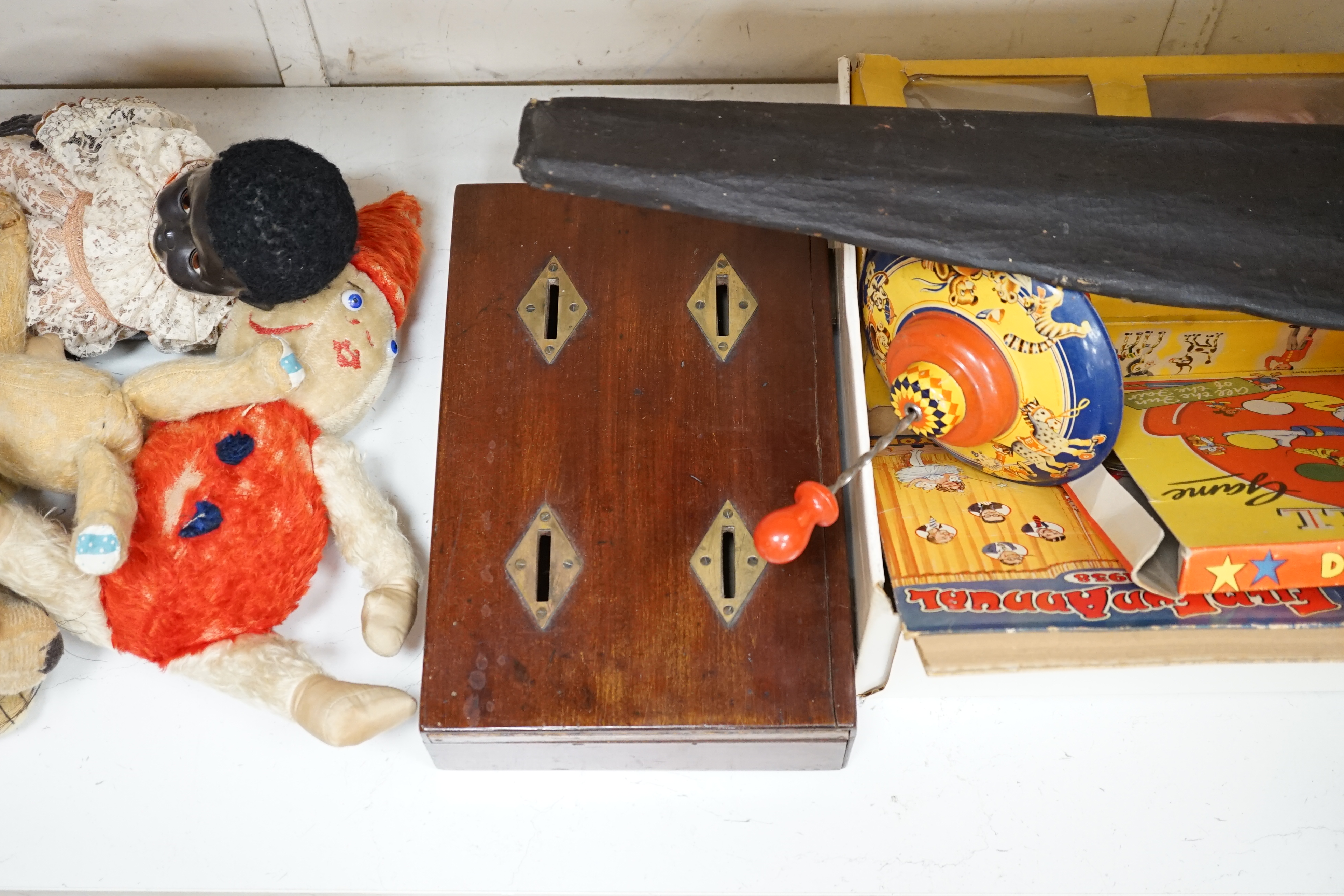 An early 20th century cased Bussey’s Hawk kite, a black walkie talkie doll, a four slot money box, an early Pelham puppet and two others, a hump backed teddy, together with various games and soft toys